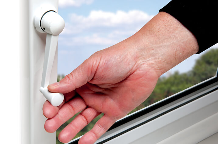 Hand twisting a handle to open a window